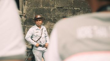 Seorang petugas keamanan profesional berdiri siap memberikan pelayanan dan menjaga ketertiban di area umum. Penguasaan keahlian komunikasi serta sertifikasi resmi menjadi modal utama dalam meniti karier di bidang pengamanan alih daya.