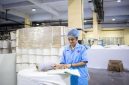 Seorang operator produksi sedang melakukan pemeriksaan kualitas produk dengan cermat di sepanjang garis perakitan pabrik manufaktur modern.
