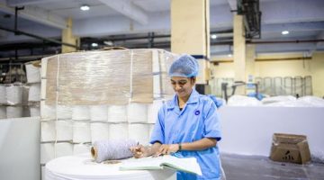 Seorang operator produksi sedang melakukan pemeriksaan kualitas produk dengan cermat di sepanjang garis perakitan pabrik manufaktur modern.
