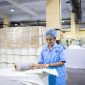Seorang operator produksi sedang melakukan pemeriksaan kualitas produk dengan cermat di sepanjang garis perakitan pabrik manufaktur modern.