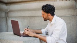 Seorang pencari kerja sedang mengedit dokumen resume digital di laptop untuk disesuaikan dengan kriteria sistem pelacak pelamar otomatis.