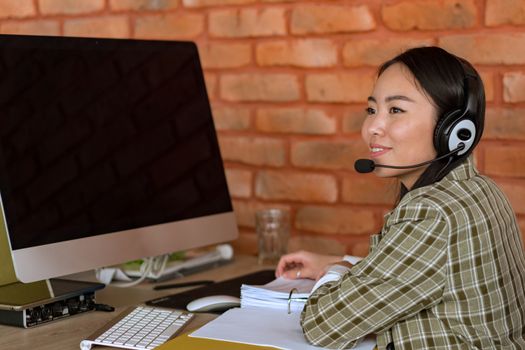 Seorang petugas layanan pelanggan alih daya sedang menangani komunikasi dengan konsumen menggunakan peranti dengar di kantor, menunjukkan profesionalisme serta fokus tinggi dalam menyelesaikan setiap kendala pengguna.