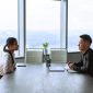 Dua manajer sumber daya manusia sedang mengevaluasi berkas lamaran kerja calon karyawan dalam sesi wawancara di kantor.