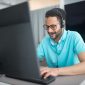 Seorang agen alih daya layanan pelanggan sedang melayani pertanyaan konsumen dengan ramah dan profesional menggunakan headphone di kantor pusat operasional.