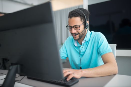 Seorang agen alih daya layanan pelanggan sedang melayani pertanyaan konsumen dengan ramah dan profesional menggunakan headphone di kantor pusat operasional.
