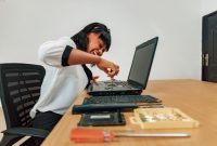 Seorang profesional muda sedang menganalisis data proyek energi terbarukan menggunakan perangkat tablet canggih di kawasan industri hijau.